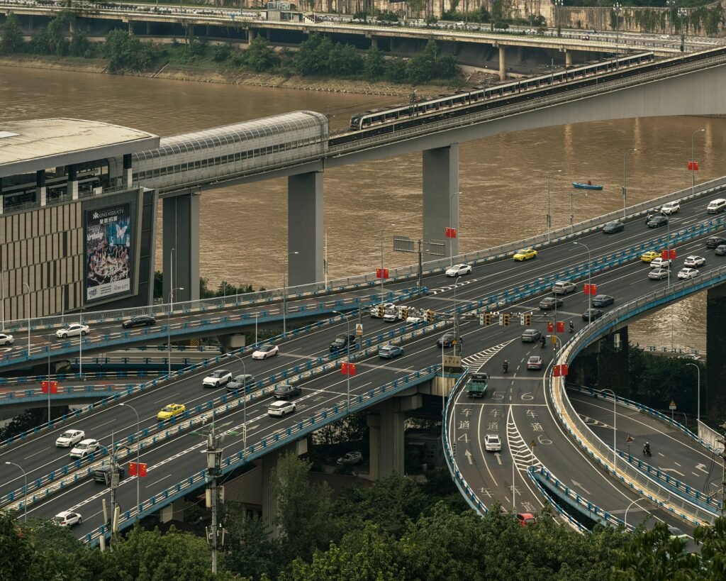 pexels-photo-34124641-34124641 High-angle view of cars on a busy highway intersection near a river in an urban setting.