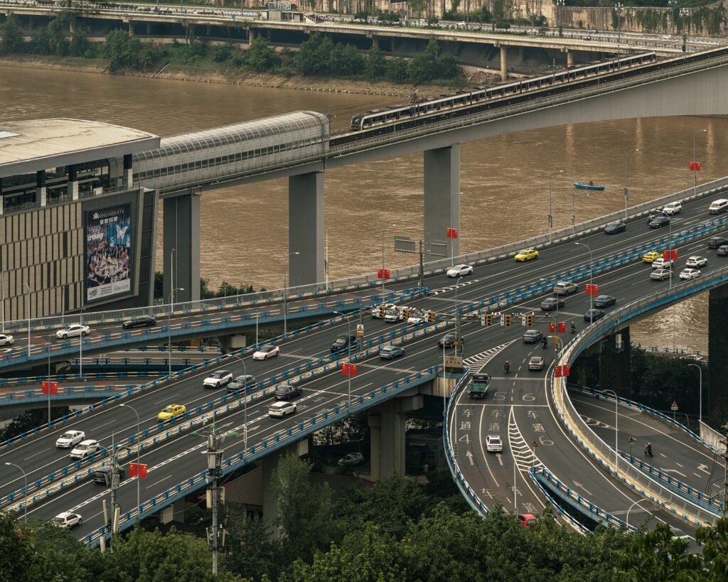 pexels-photo-34124641-34124641 High-angle view of cars on a busy highway intersection near a river in an urban setting.