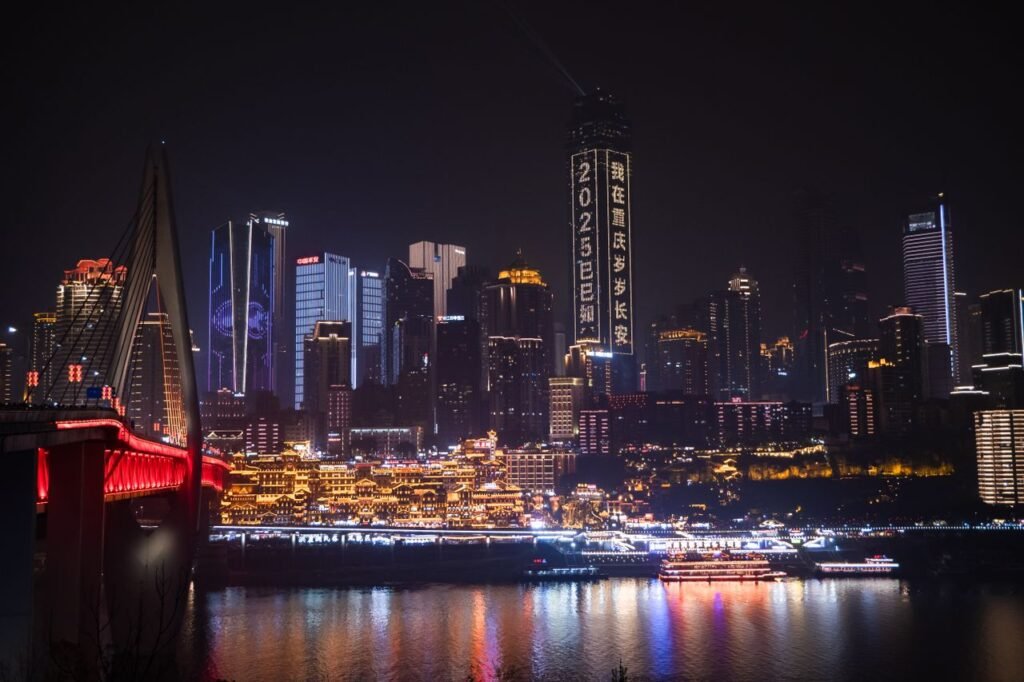 Chongqing cityscape at night featuring lit modern skyscrapers and illuminated bridge.