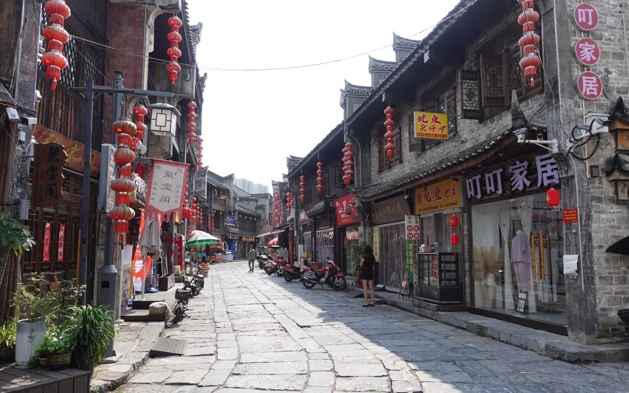 A charming Chinese street adorned with red lanterns, featuring traditional buildings and shops.